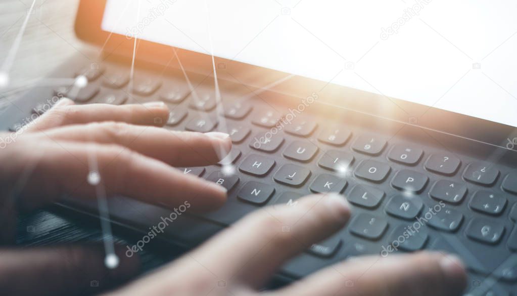 Close-up view of male hands typing on electronic tablet keyboard-dock station. Businessman working at office and using electronic pen and device.