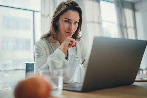 Przystojny bizneswoman pracy na laptopie w jej miejscu pracy w nowoczesnym biurze. Niewyraźne tło. — Zdjęcie stockowe