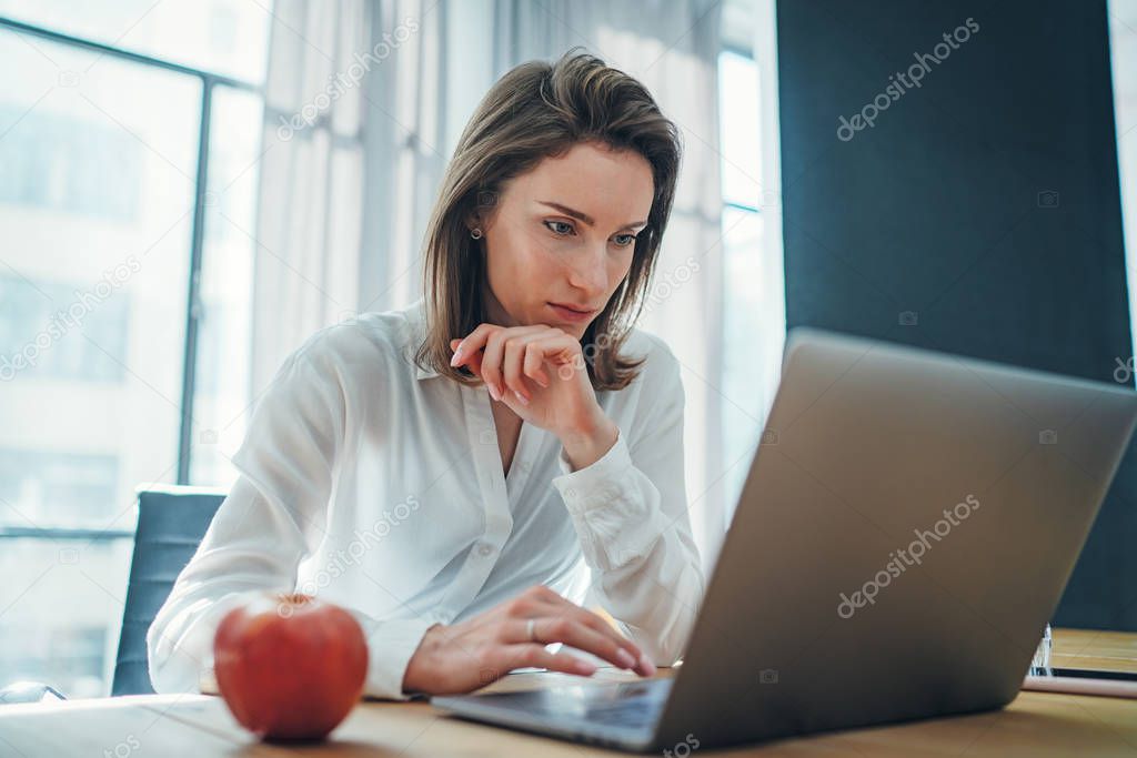 Young entrepreneur female using mobile laptop for looking a new business solution during work process at office.Blurred background.