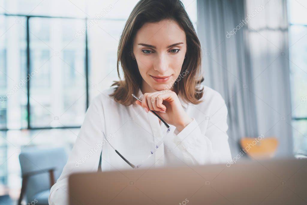 Portrait of pensive confident businesswoman working with laptop computer at modern office.Blurred background.