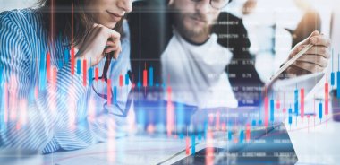 İki collegues monitörde mali grafikler ve istatistikleri ile ön dizüstü bilgisayar oturuyor. Çift pozlama.