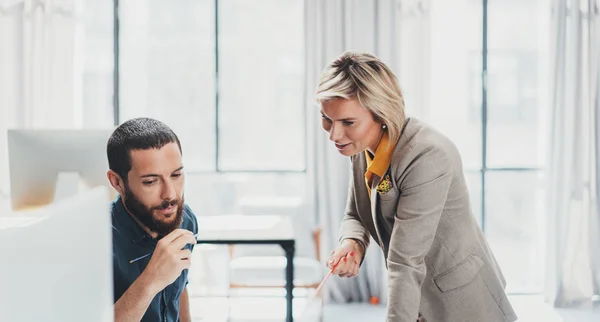 Foto von zwei jungen Mitarbeitern, die im Büro am mobilen Laptop arbeiten. Frau zeigt auf Touchscreen. — Stockfoto