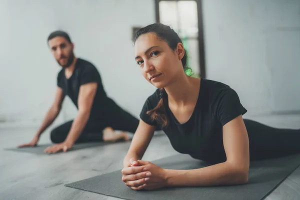 Yoga Practice Exercise Class Concept. Two beautiful people doing exercises.Young woman and man practicing yoga indoors. — Stock Photo, Image