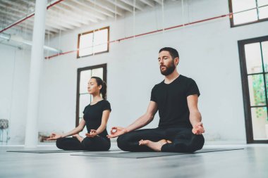 Yoga alıştırma sınıfı konsepti. Egzersiz yapan iki güzel insan. Genç kadın ve erkek içeride yoga yapıyor..