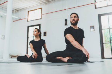 Yoga alıştırma sınıfı konsepti. Egzersiz yapan iki güzel insan. Genç kadın ve erkek içeride yoga yapıyor..
