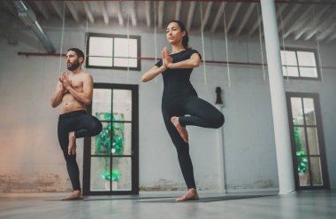 Yoga alıştırma sınıfı konsepti. Evde yoga yapan genç bir kadın ve erkek. Egzersiz yapan iki sporcu..