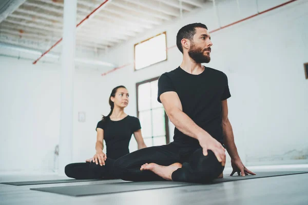 Yoga Practice Exercise Class Concept. Two beautiful people doing exercises.Young woman and man practicing yoga indoors. — Stock Photo, Image