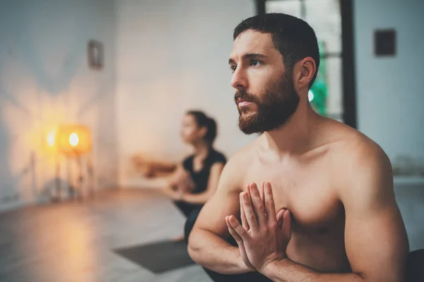 Concepto de clase de ejercicio de práctica de yoga. Mujer joven y hombre practicando yoga en interiores. Dos deportistas haciendo ejercicios . — Foto de Stock