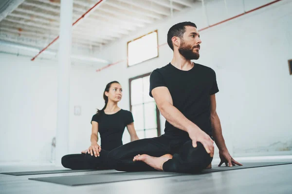 Yoga Pratica Esercizio Concetto di classe. Due belle persone che fanno esercizi. Giovane donna e uomo che praticano yoga al chiuso . Immagine Stock