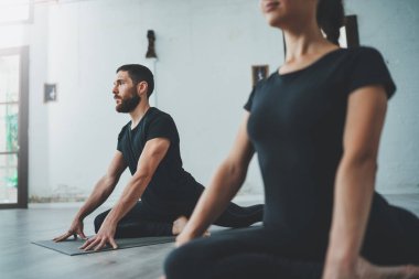 Yoga alıştırma sınıfı konsepti. Egzersiz yapan iki güzel insan. Genç kadın ve erkek içeride yoga yapıyor..