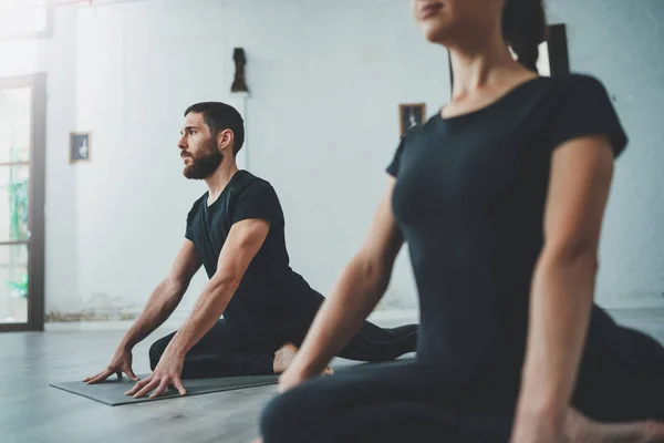 Yoga Pratica Esercizio Concetto di classe. Due belle persone che fanno esercizi. Giovane donna e uomo che praticano yoga al chiuso . Immagine Stock