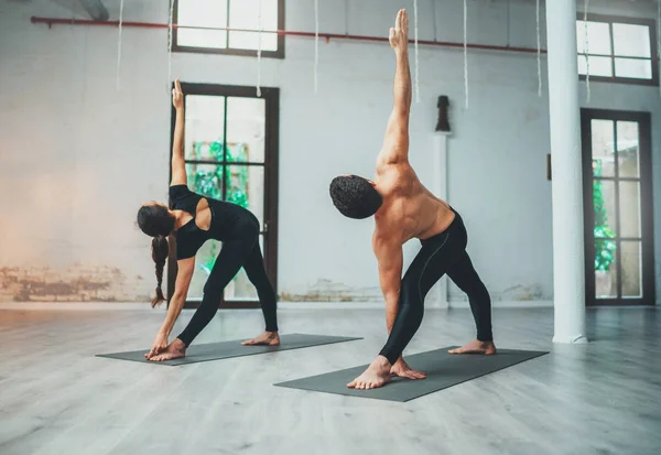 Couple of young sporty people practicing yoga lesson with partner. Two people doing yoga exercises. — Stock Photo, Image