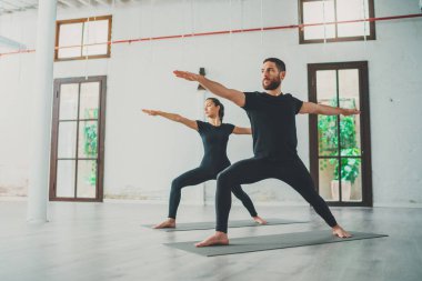 Genç sporcu erkek ve kadın stüdyoda yoga egzersizleri yapıyorlar. Partneriyle yoga dersi alan birkaç genç sporcu.