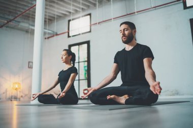 Yoga alıştırma sınıfı konsepti. Egzersiz yapan iki güzel insan. Genç kadın ve erkek içeride yoga yapıyor..