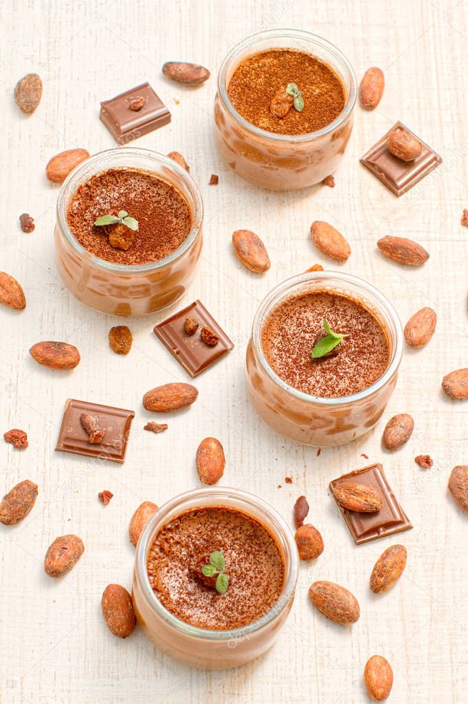 Chocolate dessert panna cotta in glass jars with raw cocoa beans, top view