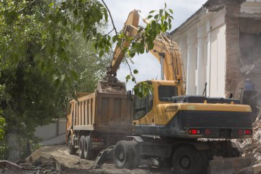 Tekerlekli Ekskavatör inşaat enkaz ve enkaz bir damperli kamyon gövdesinde imha sonra eski bina duvarlarında yükleme yapmak