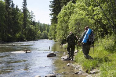 Forester ve mat sırtı ve trek bir tüfek arkasında dağ Nehri uyku Müfettiş bir sırt çantası ile orman içinde taşlar arasında akan