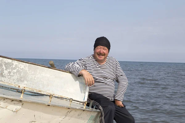 Portrait of a mature sailor man on a light aluminum boat on the shore of Lake Baikal