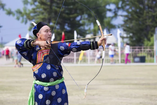 Competitions in shooting from a sports bow in Siberia. Mongolian competitions in archery. The sportsman is dressed in a traditional Buryat-Mongolian suit, shooting with his arrows during a national holiday.