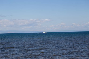 Bir zevk tekne Baykal Dağları nın arka planda boyunca yelken ve yedekte hafif bir tekne sürükler.