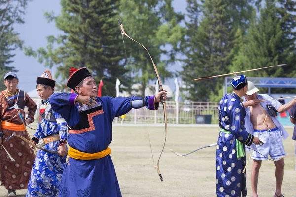 Competitions in shooting from a sports bow in Siberia. Mongolian competitions in archery. The sportsman is dressed in a traditional Buryat-Mongolian suit, shooting with his arrows during a national holiday.