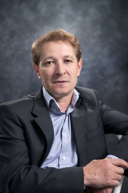 Stüdyoda gri bir arka plan üzerinde bir kravat olmadan değil zengin bir orta yaşlı işadamı portresi