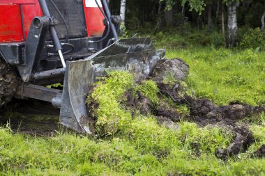 Patinaj traktörü yangın önleme şeridini açıyor. Patinaj traktörü bıçakla kesiyor ve en üst katmandaki toprağı çimlerle birlikte yığına yolluyor. Ormandaki yangınların önlenmesi.