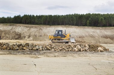 Buldozer taşır ve toprak ve moloz dolgu yolun üzerinde yayılır