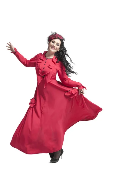 年轻的女人刺痛黑发在一个长长的红色礼服跳舞和摆姿势在演播室 — 图库照片