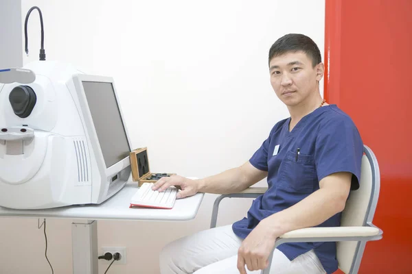 Asiático Oftalmologista Masculino Está Seu Local Trabalho Trabalhando Com Dispositivo — Fotografia de Stock