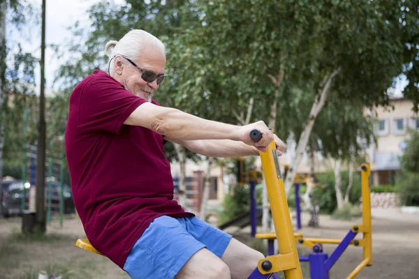 Senior man trains on sporting equipment on open air