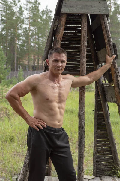 Attractive muscular man in a wooded area,