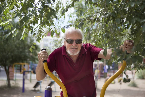 Senior man trains on sporting equipment on open air