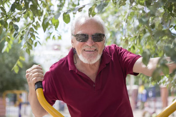 Senior man trains on sporting equipment on open air