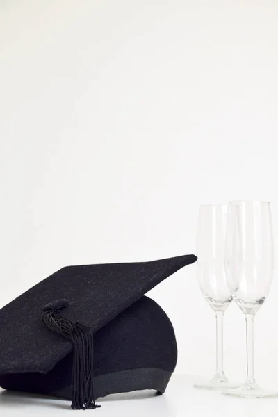 Graduation celebration with graduation cap and empty champagne glasses on table