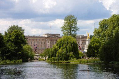 Buckingham Sarayı'nın önünde gölet ve ağaçlar var. Kaldırılı bayrak. Londra, İngiltere.