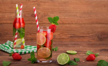 Çilek, limon ve nane bir ahşap zemin üzerine uzun bir bardak taze limonata