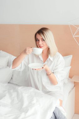 Güzel kadın evde yatağında oturup bir kahve içme