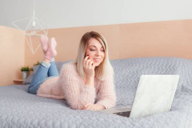 Şoförünün yatakta yatan bir dizüstü bilgisayar üzerinde çalışan mutlu rahat güzel kadın