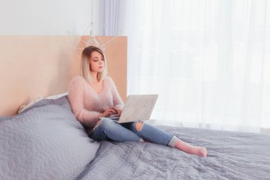 Şoförünün yatakta oturup bir dizüstü bilgisayar üzerinde çalışan mutlu rahat güzel kadın