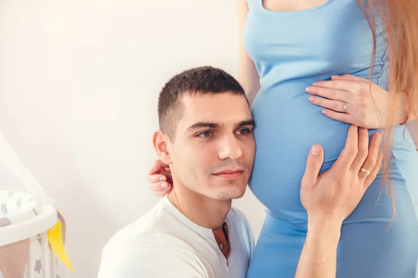 寝室に立って彼の素敵な妊娠中の妻の腹を聞いている男性のクローズ アップ — ストック写真