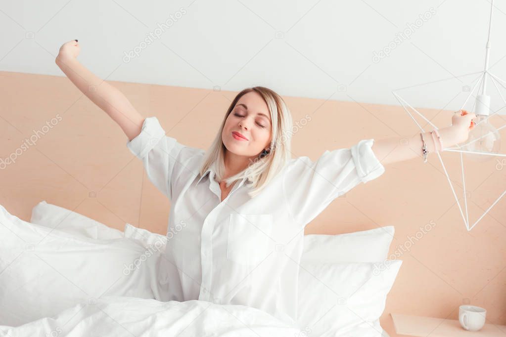 Young woman stretching out sitting on her bed