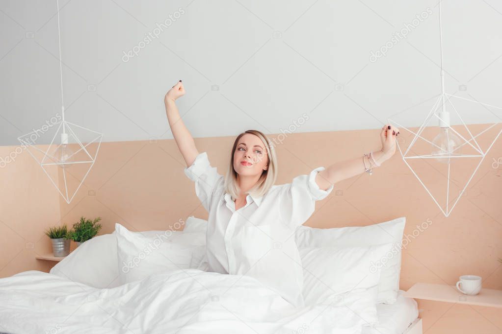 Young woman stretching out sitting on her bed