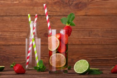 Çilek, limon ve nane bir ahşap zemin üzerine uzun bir bardak taze limonata