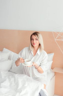 Güzel kadın evde yatağında oturup bir kahve içme