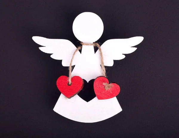 白色天使的圣诞装饰品在黑色背景上有两颗红色的心 — 图库照片
