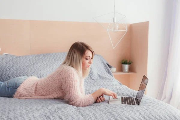 Şoförünün yatakta yatan bir dizüstü bilgisayar üzerinde çalışan mutlu rahat güzel kadın