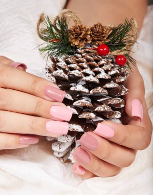 Elinde pembe bir çam Noel dekorasyonu tutan oje ile renkli uzun yapay manikürlü tırnaklar