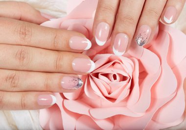 Hands with artificial french manicured nails and pink rose flower clipart