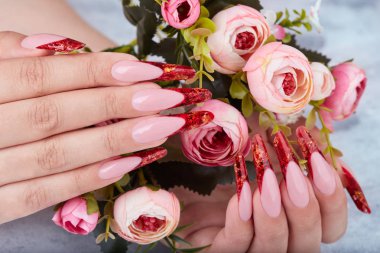 Uzun kırmızı yapay Fransız manikürlü çivi tutan eller pembe gül çiçekler